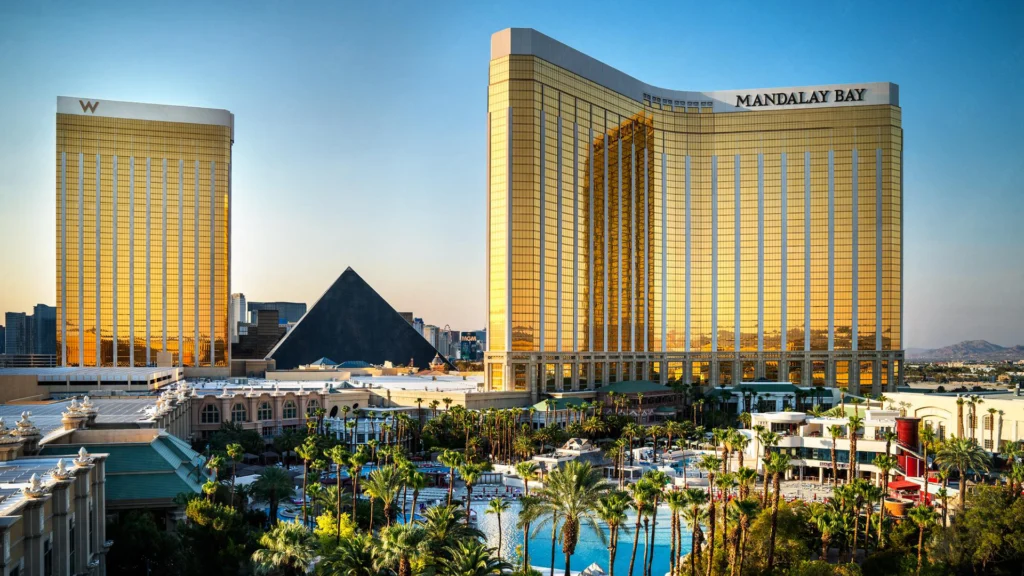 Las Vegas'taki Mandalay Bay Oteli ve Kumarhanesi'nin altın rengi cephesi, arka planda havuz alanı ve Luksor Piramidi