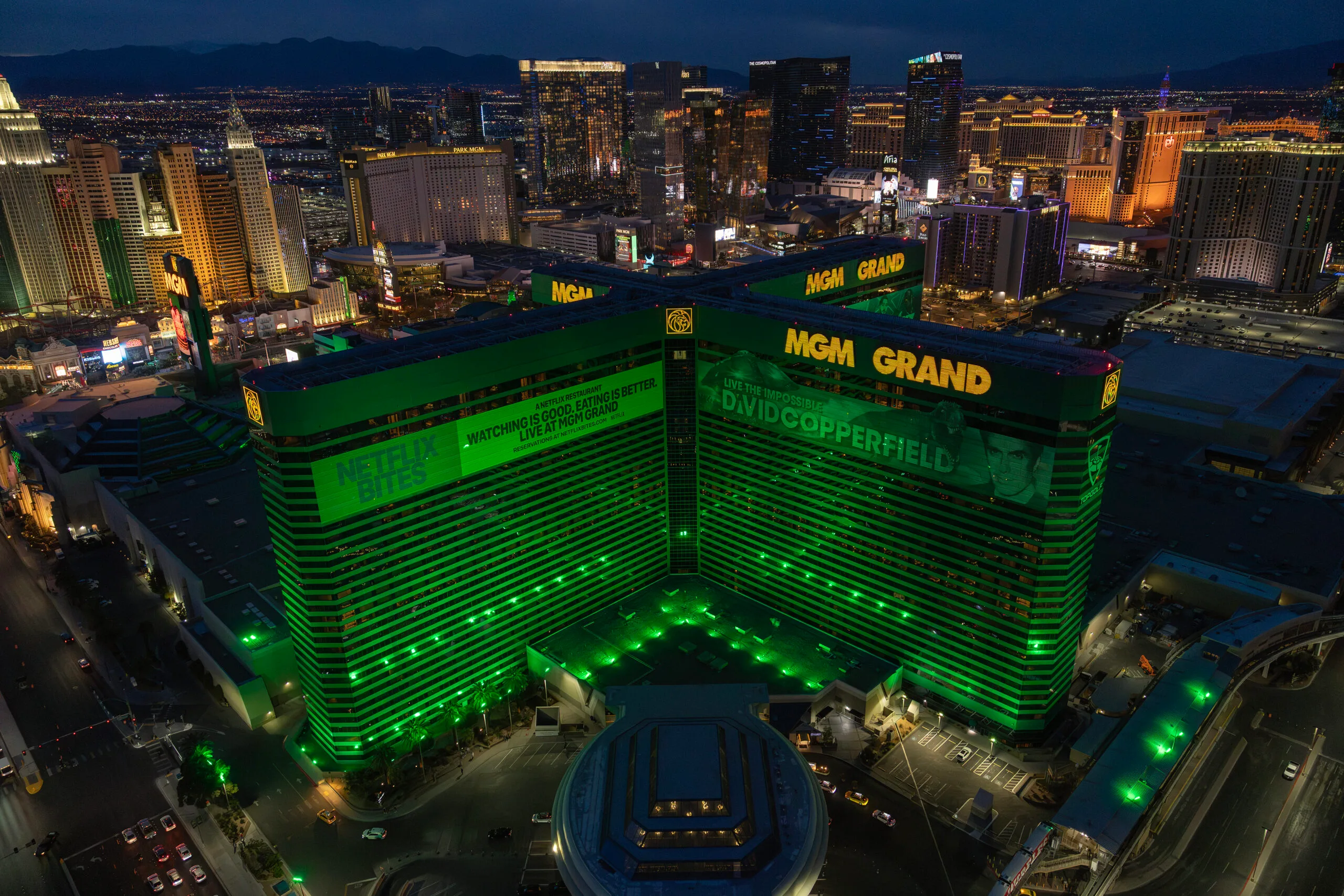 MGM Grand Las Vegas aerial view at night, showing the illuminated hotel tower and surrounding Las Vegas Strip skyline.