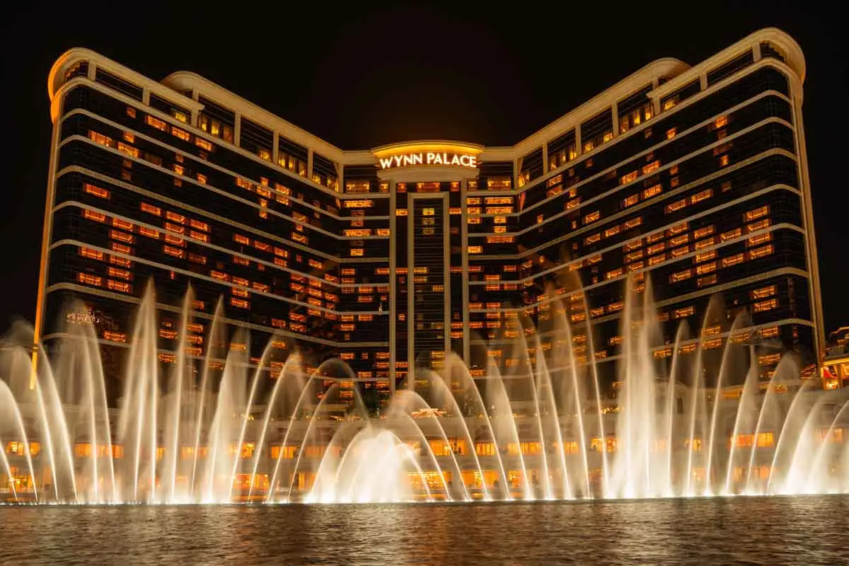 Wynn Palace Macau at night with illuminated hotel towers and fountain show in front of the resort.